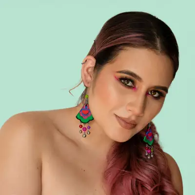 Retrato de mujer con maquillaje artístico y aretes de colores